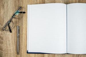 diário de caderno em branco com caneta prateada e óculos foto