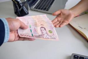 o patrão paga salário aos empregados é a compensação pelo trabalho feito para a empresa. moeda tailandesa e conceito de baht tailandês foto