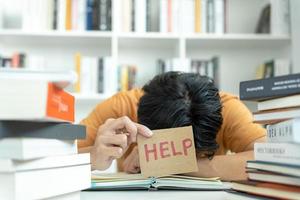 homem estudante asiático tem ansiedade por causa dos exames, o homem se prepara para o teste e aprende lições na biblioteca. estresse, desespero, pressa, leitura mal-entendida, desencorajado, expectativa, conhecimento, cansado foto