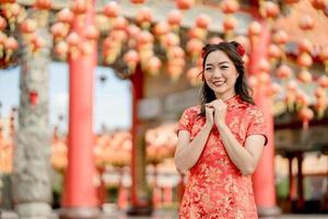 feliz Ano Novo Chinês. mulher asiática usando vestido cheongsam qipao tradicional com gesto de parabéns no templo budista chinês. foto