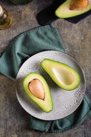 metades de abacate em um prato na mesa. nutrição saudável de vitaminas. vista superior e vertical foto