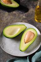 metades de abacate em um prato na mesa. nutrição saudável de vitaminas. visão vertical foto