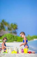 meninas construindo um castelo de areia foto