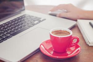 xícara de café vermelha com uma pessoa trabalhando em um laptop foto