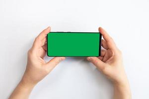 mulher segurando um celular com tela verde e fundo branco foto