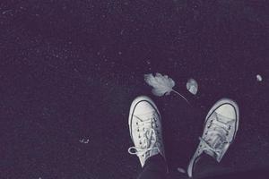 pessoa usando tênis branco em um chão escuro