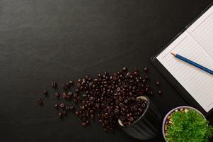 mesa preta com caderno e grãos de café foto