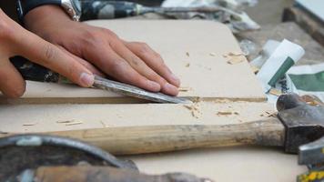 mãos de homem segurando um cinzel esculpindo uma tábua de madeira foto