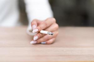 closeup mão de mulher fumando, conceito de estilo de vida pouco saudável foto