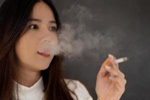 mulher asiática fumando com fumaça de cigarro foto