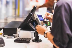 mulheres do consumidor assinando em uma tela sensível ao toque da máquina de transação de venda de cartão de crédito no mercado de jantar. foto