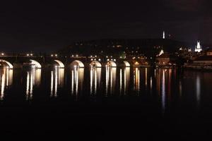 noite ponte sobre o rio com lanternas em praga, república tcheca. foto