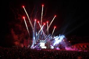 saudação e fogos de artifício em um palco de música com holofotes à noite. foto