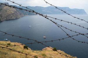 fronteira militar de arame farpado no mar nas montanhas foto