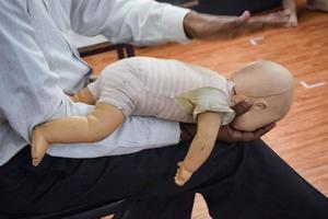 homem realizando RCP em manequim de boneca de treinamento de bebê com compressão de uma mão. treinamento de primeiros socorros - ressuscitação cardiopulmonar. curso de primeiros socorros em manequim cpr, conceito de treinamento de primeiros socorros cpr foto