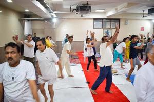 delhi, índia, 19 de junho de 2022 -sessão de ioga em grupo para pessoas de diferentes faixas etárias no templo balaji, vivek vihar, dia internacional da ioga, grande grupo de adultos participando de aulas de aeróbica no templo foto