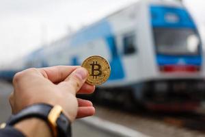 mão segurando o trem de dinheiro virtual bitcoin dourado foto