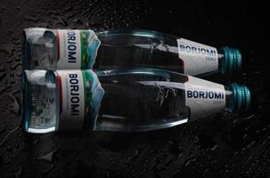 krasnoyarsk, rússia - 21 de outubro de 2022 duas garrafas de água mineral natural borjomi em um fundo preto. foto