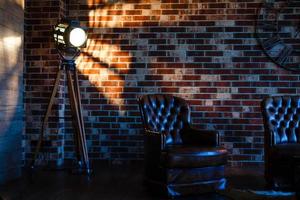interior do sotão simulado parede de bloco cinza com cadeira de couro e lâmpada de fonte de luz vintage foto