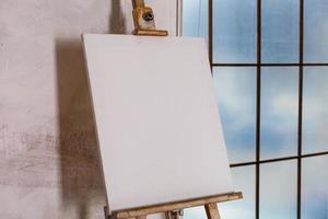 tela artística vazia branca em um cavalete para desenhar imagens por um artista em um fundo cinza foto