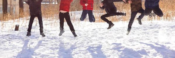 grupo de crianças alegres pulando na neve no inverno foto