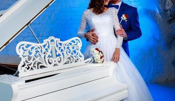 uma noiva e um noivo perto de um piano branco foto