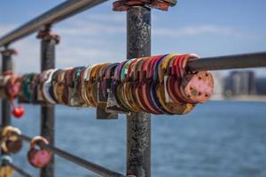 uma fechadura em forma de coração, símbolo de amor e fidelidade com um lago ao fundo, está pendurada na cerca da ponte. o castelo em forma de coração simboliza lealdade e amor foto