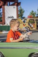 um menino dirigindo um carro infantil. emoções alegres. crianças, retrato. foto