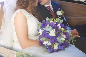 lindo casal jovem sorrindo alegremente no dia do casamento sentado na limusine foto