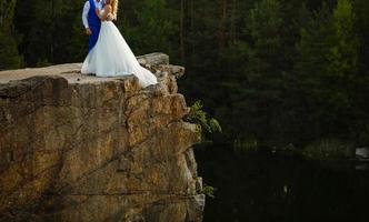 lindo casal de noivos noivos no dia do casamento ao ar livre na rocha de montanhas no fundo do mar. casal feliz ao ar livre na natureza, luzes ensolaradas suaves. foto