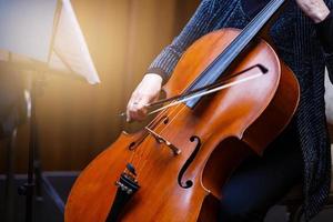 uma jovem toca violoncelo no escuro. mãos no violoncelo foto