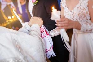 o padre colocando uma aliança no dedo do noivo durante o casamento tradicional na igreja foto