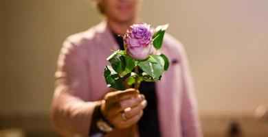 mão de homem de negócios com flor rosa vermelha em fundo branco foto