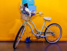 bicicleta de decoração com uma cesta de lindas flores em um fundo amarelo foto