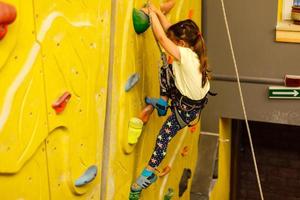menina escalando uma parede de pedra interior foto