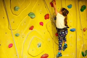 menina escalando uma parede de pedra interior foto