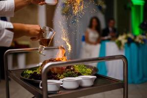 chef, derramando álcool em uma frigideira com fogo foto