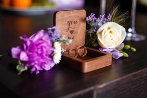 lapela de casamento. anéis de ouro estavam em uma caixa de madeira. composição branca roxa. foto