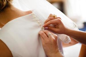 Casamento. dama de honra preparando a noiva para o dia do casamento. dama de honra ajuda a prender um vestido de noiva a noiva antes da cerimônia. vestido de noiva de luxo close-up. melhor manhã de casamento. conceito de casamento foto