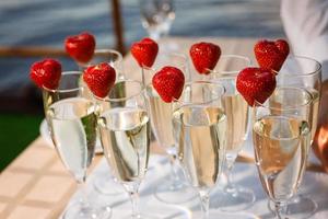 garçom de pé com taças de champanhe ao lado da mesa de casamento arranjada foto