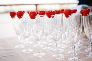 garçom de pé com taças de champanhe ao lado da mesa de casamento arranjada foto