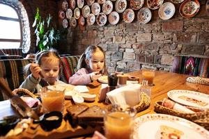 família tendo uma refeição juntos no autêntico restaurante ucraniano. as crianças das meninas comem bolinhos. foto