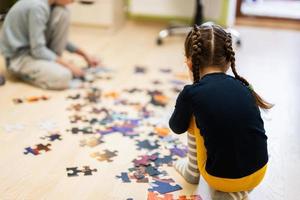 crianças conectando peças de quebra-cabeça em um quarto infantil no chão de casa. diversão em família atividade lazer. foto