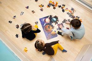 crianças conectando peças de quebra-cabeça em um quarto infantil no chão de casa. diversão em família atividade lazer.