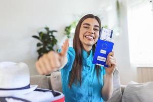 mulher feliz planejando uma viagem durante a pandemia de covid-19, preparando uma mala. mulher preparando a viagem de férias. segurando passaporte, passagem e teste negativo de coronavírus na mão foto