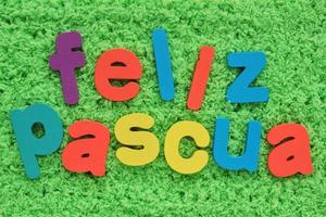 feliz páscoa, feliz páscoa em letras coloridas espanholas em fundo de grama verde. conceito de composição de primavera de férias. ideia criativa para cartão, cartaz, banner, convite. vista superior, configuração plana foto