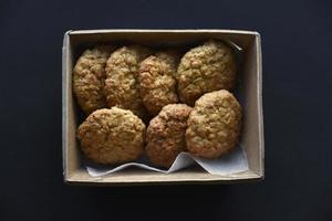 deliciosos biscoitos de aveia em uma caixa de papelão em um fundo preto. biscoitos doces. um lanche doce para o chá. foto