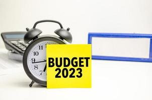 orçamento 2023 cartão amarelo com despertador e calculadora foto