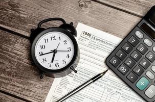 formulário de imposto de vista superior 1040 com caneta, calculadora e despertador preto. hora do imposto. documento financeiro.