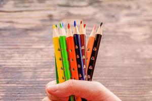 lápis de cor para desenho. lápis amarelos azuis pretos vermelhos verdes à disposição no fundo de madeira. foto